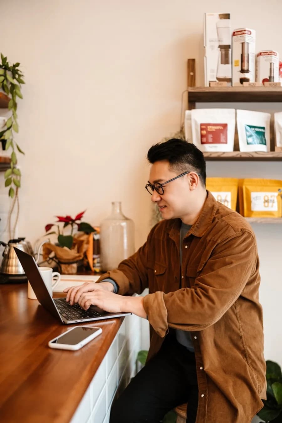 Business owner reviewing spend at a laptop in a small shop