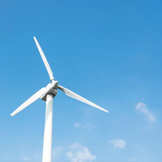 Wind turbine against a bright blue sky at a renewable energy site