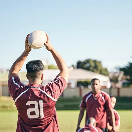 Rugby player preparing to throw the ball during team training
